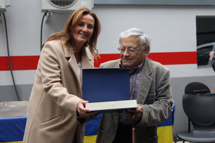 La ministra de Cultura, Joventut i Esports, Olga Gelabert, entregant un reconeixement a Sergi Mas per la seva trajectòria en l'elaboració dels cartells de la fira aquest dissabte.